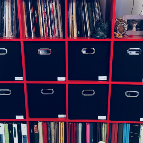 PHoto of a cube bookshelf with bins. There are 8 bins with labels, each containing different medical supplies.