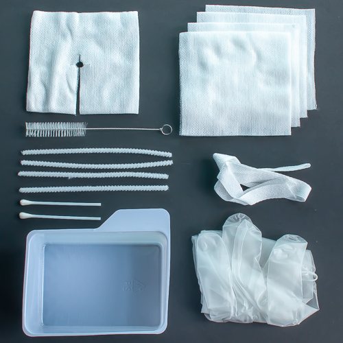 A photo taken from above of medical supplies neatly laid out on a table. Inludes a tray, surgical gloves, trach tie, gauze, split sponge, wire brush, pipe cleaners, and cotton swabs.
