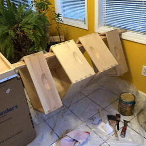 Photo of four wooden beehive frames, resting on a board, prepped to be painted.
