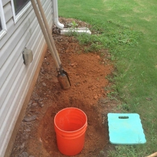 photo of yard where grass dug up and hole in the ground with bucket2