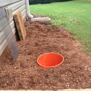 photo of yard where grass dug up and hole in the ground with bucket