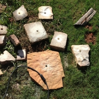 flagstone laying on the ground, with holes drilled in them by a hammer drill