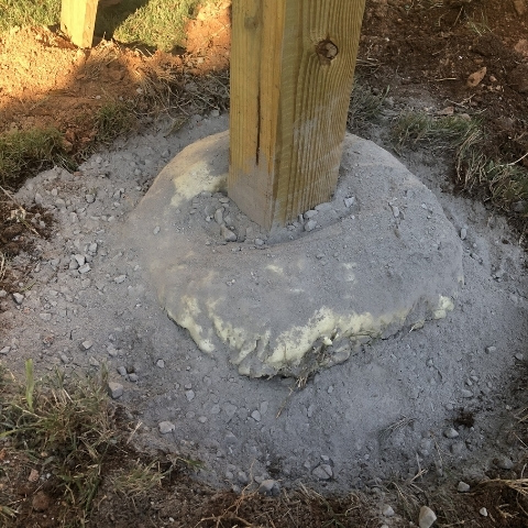 photo of wooden post in the ground with dry concrete mix poured at bottom prior to setting